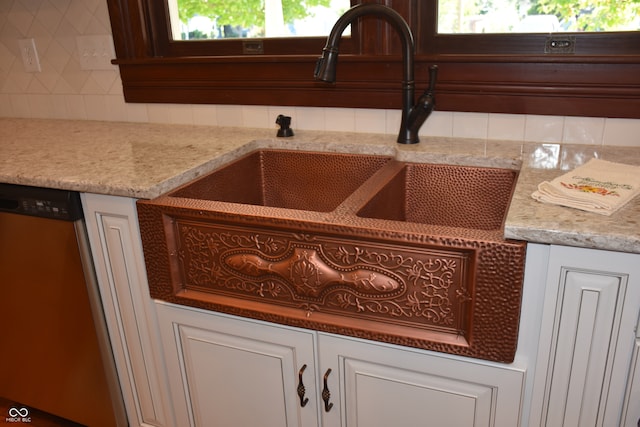 interior details featuring dishwasher, light stone counters, tasteful backsplash, sink, and white cabinets