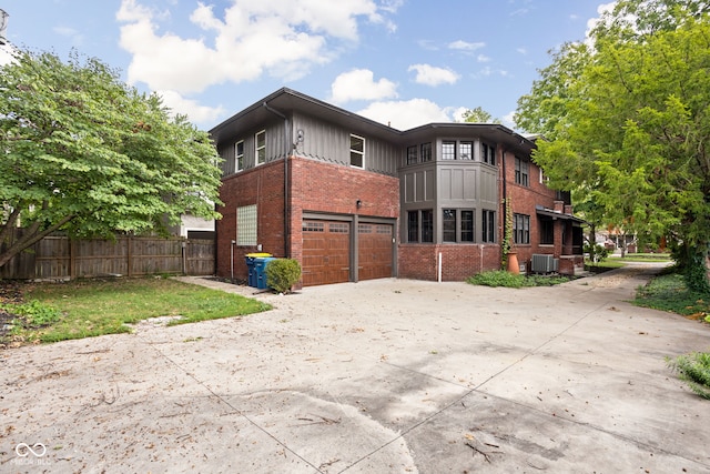 rear view of house featuring brick siding, an attached garage, fence, cooling unit, and driveway