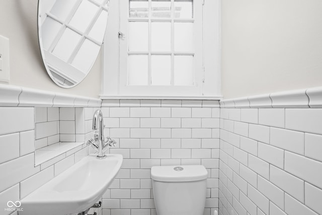 bathroom featuring tile walls, toilet, and sink