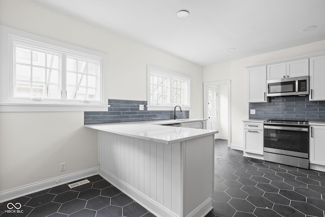 kitchen with backsplash, appliances with stainless steel finishes, light countertops, and white cabinetry