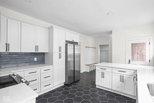 kitchen with stainless steel refrigerator, white cabinetry, and tasteful backsplash