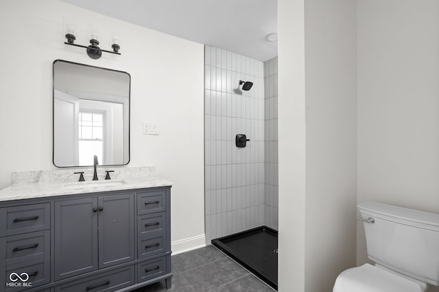 full bath featuring tile patterned flooring, tiled shower, toilet, and vanity