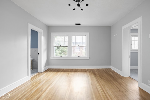 spare room featuring visible vents, light wood-type flooring, and baseboards