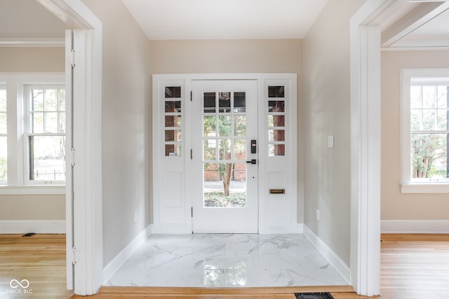 foyer with crown molding and light hardwood / wood-style floors