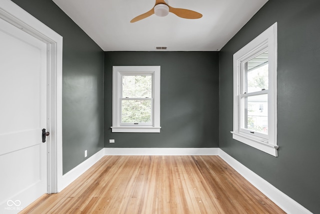 empty room with a healthy amount of sunlight, ceiling fan, and wood-type flooring