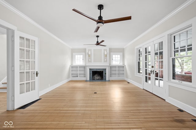 unfurnished living room with french doors, a fireplace with flush hearth, ornamental molding, and light wood finished floors