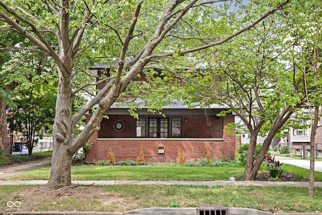 view of front facade featuring brick siding, a front lawn, and fence