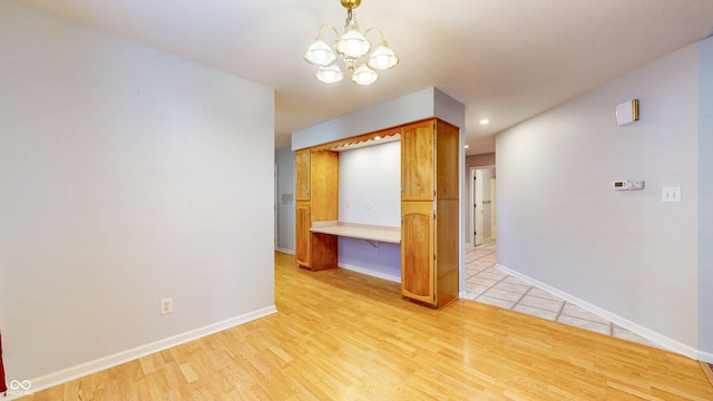 unfurnished room with a notable chandelier and light hardwood / wood-style floors