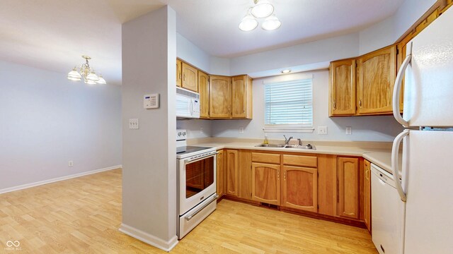 kitchen with a notable chandelier, white appliances, decorative light fixtures, sink, and light hardwood / wood-style floors