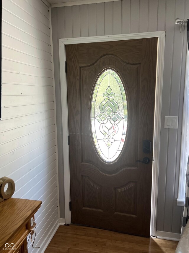 foyer entrance with hardwood / wood-style floors and wooden walls