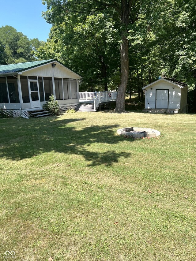 view of yard featuring a deck, a storage shed, and an outdoor fire pit