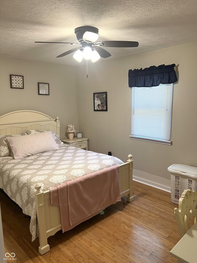 bedroom with a textured ceiling, ceiling fan, and hardwood / wood-style flooring