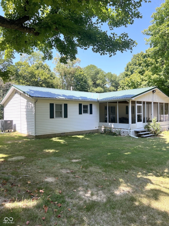 back of house featuring a lawn, a sunroom, and central AC