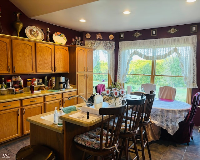 kitchen with dark tile patterned flooring, a kitchen bar, and a wealth of natural light