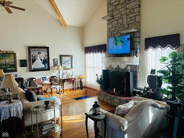 living room with a stone fireplace, a wealth of natural light, high vaulted ceiling, and wood-type flooring