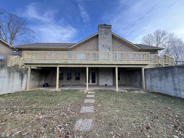 back of property with a lawn, a wooden deck, and a patio area