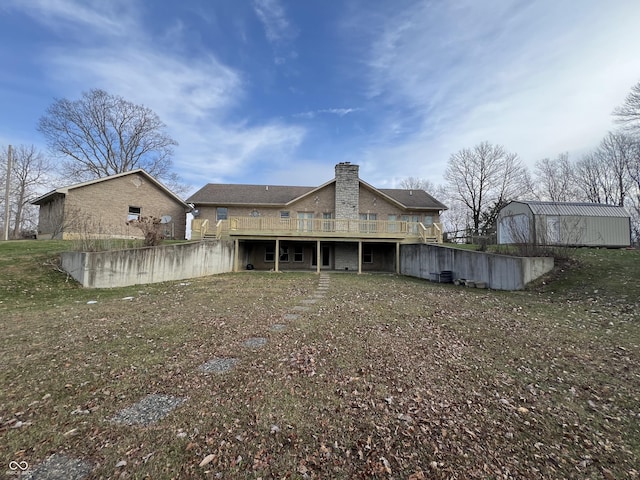 back of property with an outbuilding, a yard, and a deck