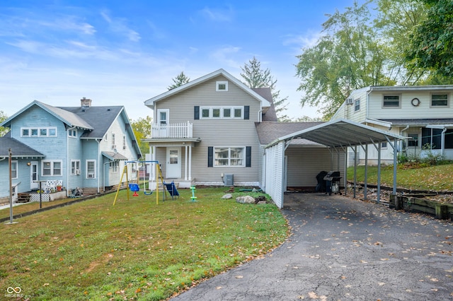 front facade with a balcony, a front lawn, and a carport