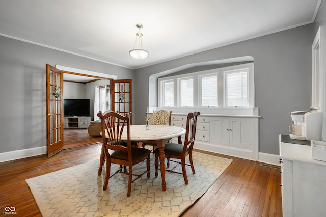 dining space with ornamental molding and dark hardwood / wood-style flooring