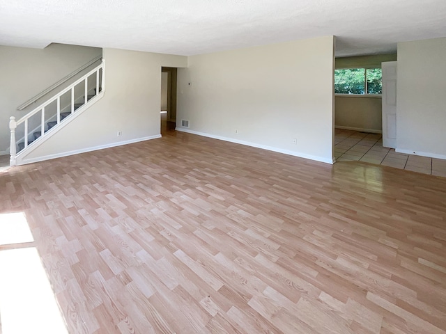 empty room with a textured ceiling and light hardwood / wood-style flooring