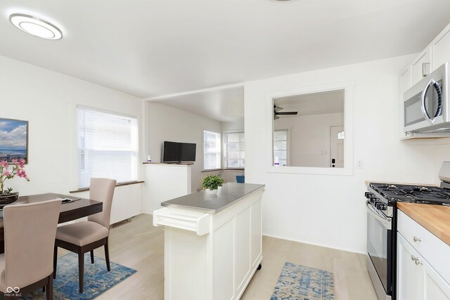 kitchen featuring white cabinets, light hardwood / wood-style flooring, stainless steel appliances, ceiling fan, and butcher block counters