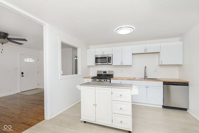 kitchen with stainless steel appliances, sink, ceiling fan, light wood-type flooring, and white cabinets