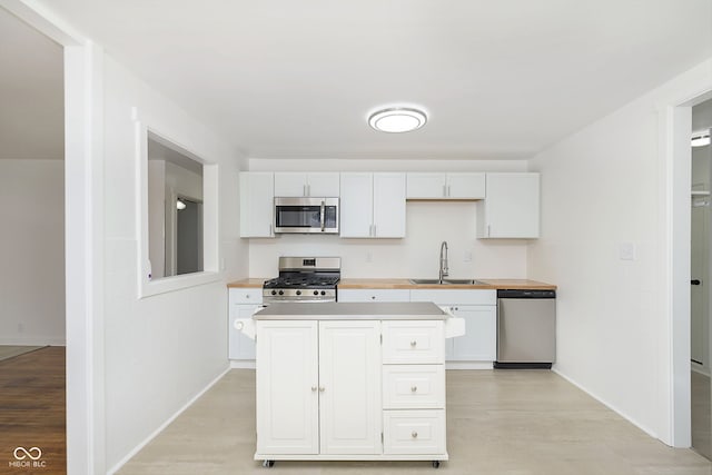 kitchen featuring white cabinets, appliances with stainless steel finishes, light hardwood / wood-style floors, and sink