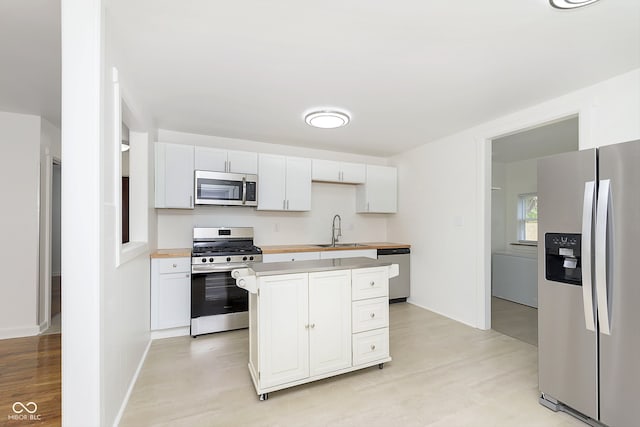 kitchen featuring a center island, stainless steel appliances, sink, and white cabinets