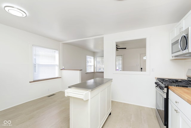 kitchen with white cabinets, light hardwood / wood-style flooring, appliances with stainless steel finishes, ceiling fan, and butcher block counters