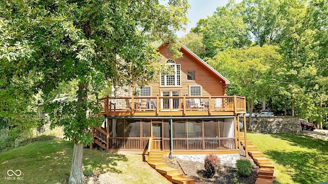 back of property featuring a deck, a yard, and a sunroom