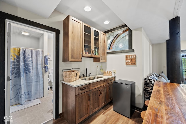 interior space with stainless steel fridge, light hardwood / wood-style floors, sink, and light stone countertops