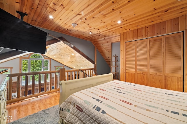 bedroom featuring vaulted ceiling, wood walls, a closet, wooden ceiling, and wood-type flooring