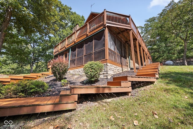 rear view of property featuring a lawn and a sunroom