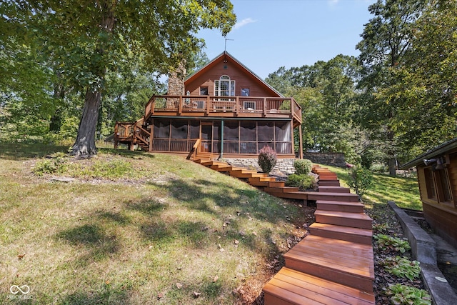 rear view of house featuring a wooden deck, a sunroom, and a lawn