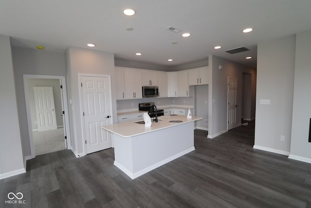 kitchen featuring dark wood-type flooring, white cabinets, sink, a kitchen island with sink, and electric range