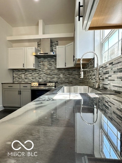 kitchen featuring white cabinetry, sink, tasteful backsplash, stainless steel electric range, and wall chimney range hood