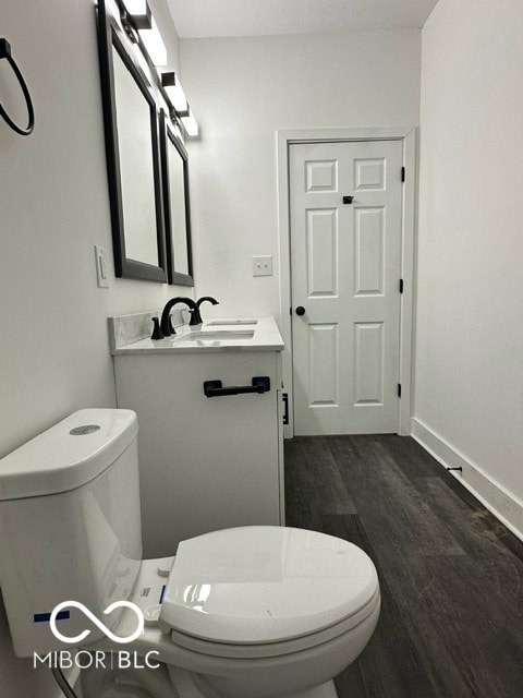 bathroom featuring toilet, vanity, and hardwood / wood-style flooring