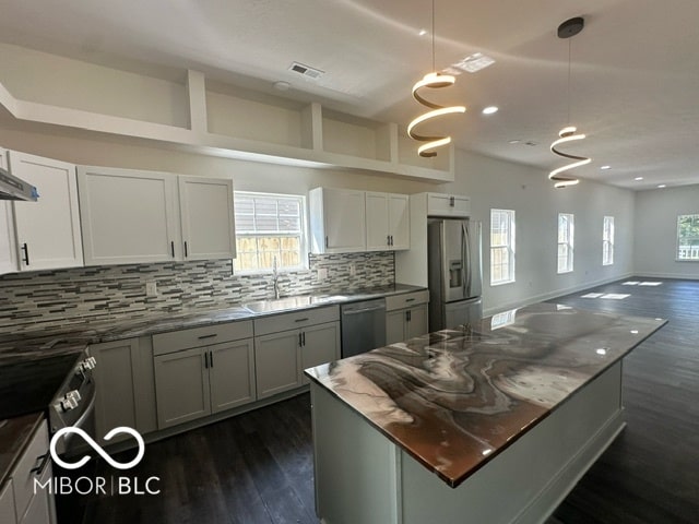 kitchen featuring white cabinetry, appliances with stainless steel finishes, hanging light fixtures, sink, and dark wood-type flooring