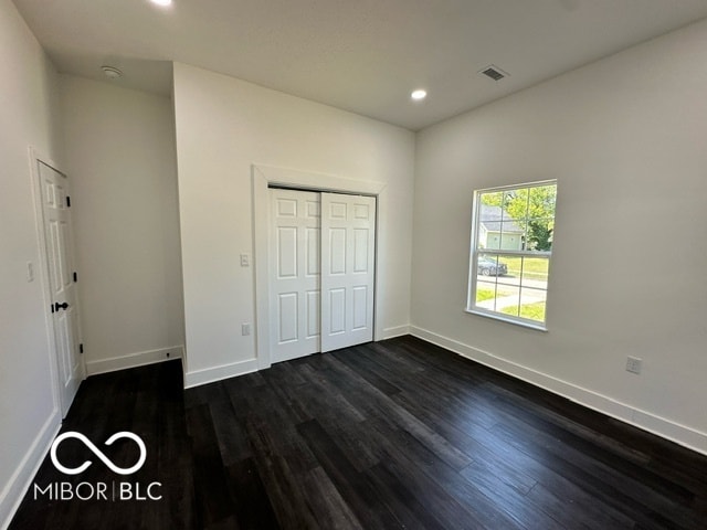 unfurnished bedroom featuring a closet and dark hardwood / wood-style floors