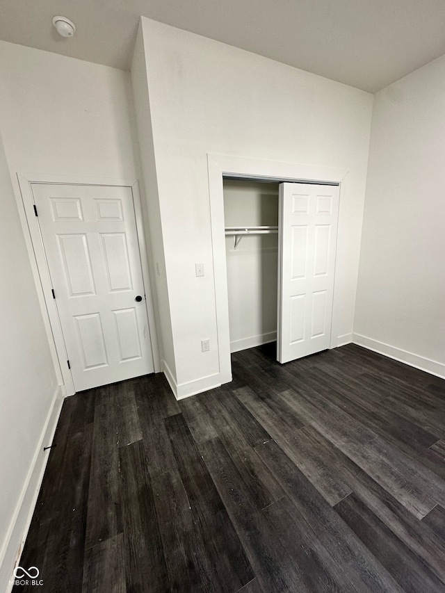 unfurnished bedroom with dark hardwood / wood-style floors and a closet