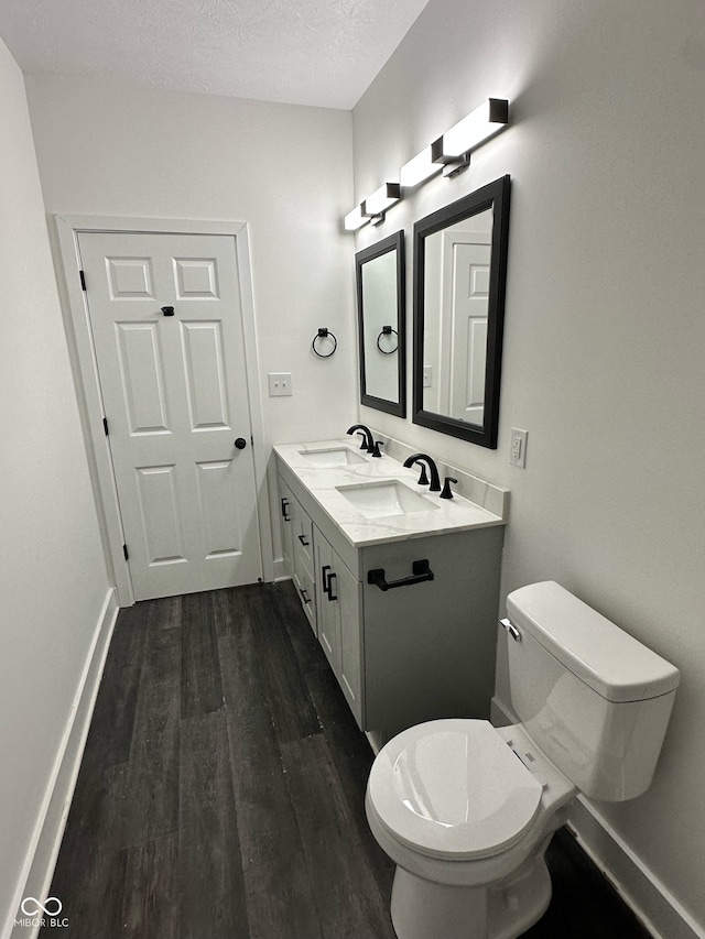 bathroom featuring toilet, vanity, wood-type flooring, and a textured ceiling