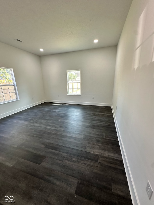 spare room with dark wood-type flooring and plenty of natural light