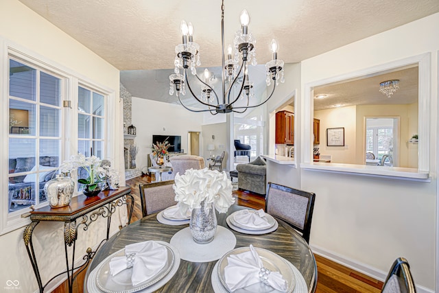 dining area with a textured ceiling, hardwood / wood-style floors, and an inviting chandelier