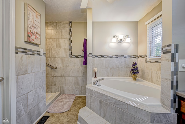 bathroom featuring tile patterned flooring, shower with separate bathtub, tile walls, vanity, and a textured ceiling