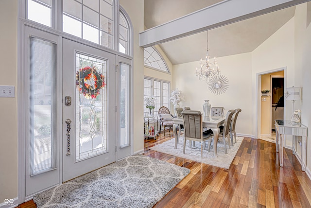 entryway with high vaulted ceiling, hardwood / wood-style floors, and an inviting chandelier