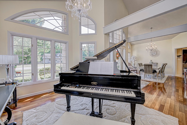 misc room with high vaulted ceiling, a wealth of natural light, hardwood / wood-style flooring, and an inviting chandelier