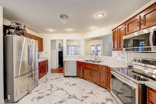 kitchen with backsplash, an inviting chandelier, appliances with stainless steel finishes, sink, and a textured ceiling