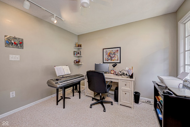 office space featuring a textured ceiling, rail lighting, ceiling fan, and light carpet