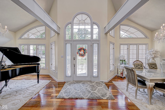 foyer entrance featuring high vaulted ceiling, a chandelier, and dark hardwood / wood-style floors