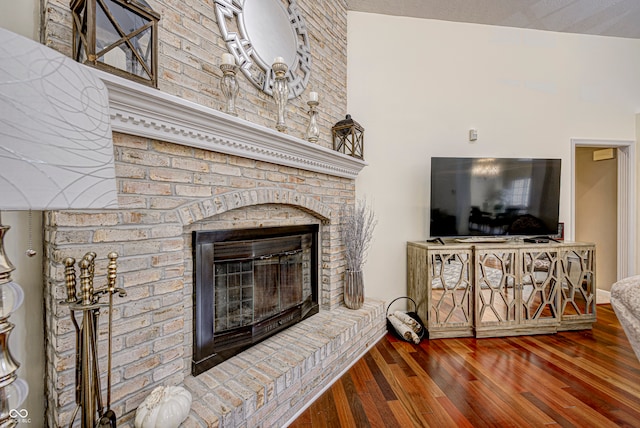 living room featuring lofted ceiling, a fireplace, and dark hardwood / wood-style floors